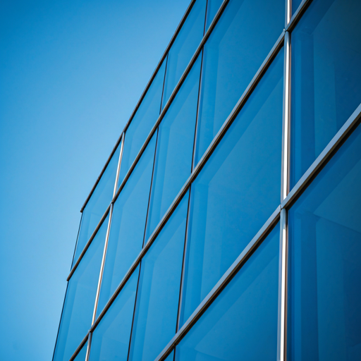 Détail architectural géométrique moderne d'un bâtiment en verre reflétant un ciel bleu vibrant